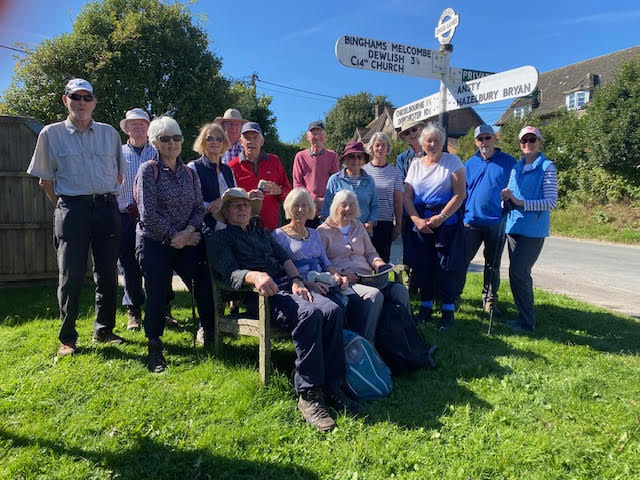 Walking group 5 pausing at signpost for a group photo.