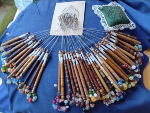 A lace in the making with a row of bobbins joined.