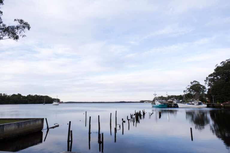 Lake with mirror waters under partially cloudy sky and balmy day.
