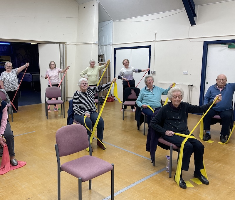 Movement To Music members sitting with resistance bands.