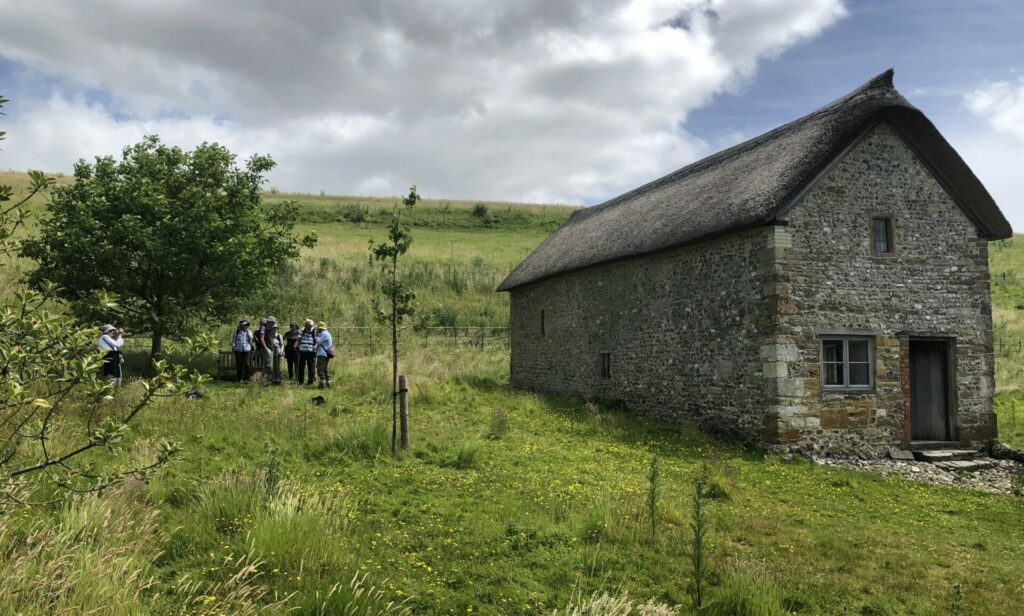 Hiking Group 1 image of the group paused for a rest next to an old thatched building. Rural scene.